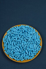 Yellow plate full of blue medicine capsules representing drug overdose