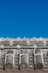 Japanese traditional grey roof tile with old spiral motif and blue sky above as background (with...