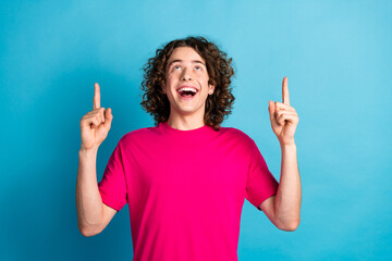 Portrait of optimistic man with curly hairdo piercing wear pink shirt look directing at logo empty...