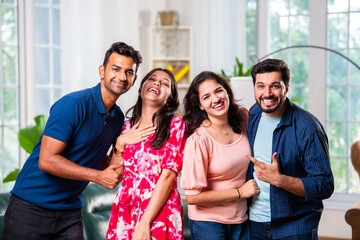 Reunion of Indian asian young friends or couple posing for a group photo inside living room