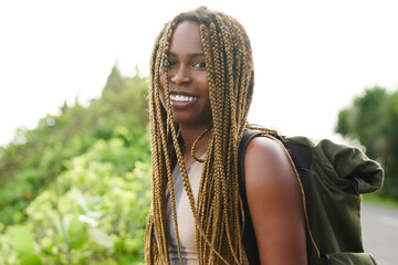Portrait of beautiful afro american female tourist with cool dreads and travel stylish backpack...
