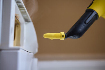 hand in gloves. Using a steam cleaner to clean a washing machine