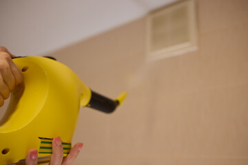 hand in gloves. Using a steam cleaner to clean the ventilation grille at home