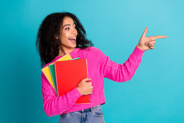 Photo of attractive teen girl hold copybooks look point empty space dressed stylish pink clothes...