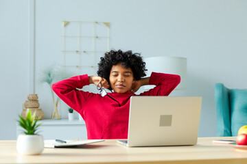 African american girl at home office relaxing stretching hands and body taking break from work on...