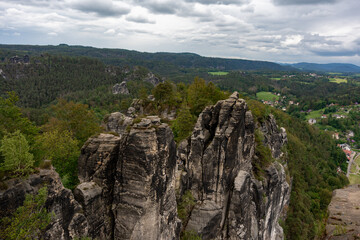 A mountain range with a town in the distance. The sky is cloudy and the mountains are covered in trees