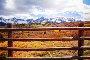 Rural mountain landscape with wooden fence in the foreground and clouds in the sky