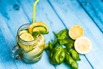 A summery, refreshing cucumber and basil cocktail in a transparent glass mug on a blue wooden...