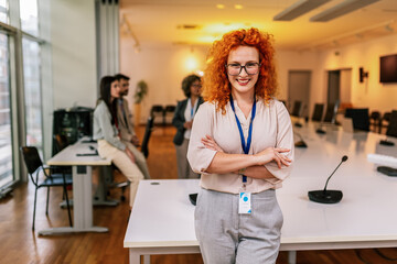 Portrait of young ginger businesswoman standing in front of her colleagues.