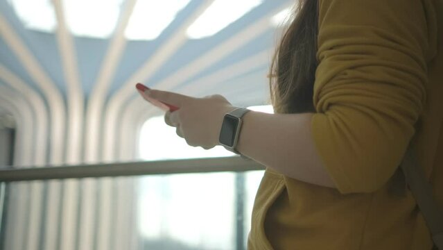 Woman hands answering messages on smartphone in the airport sitting at table. Female waiting in the departure lounge entertaining herself on the phone.
