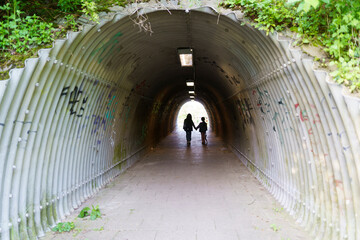 Silhouettes of two little girls with their dog against the backdrop of the light end of the tunnel