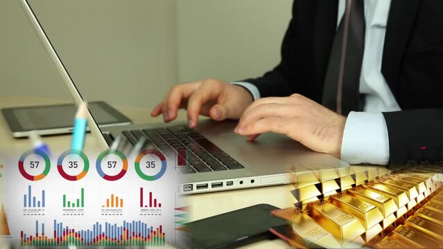 Ejecutivo emprendedor, inversionista, trabajando en su laptop y tablet con un gr&aacute;fico de valores y variaciones  de precios que se mueven, y lingotes de oro que circulan simbolizando sus ganancias.