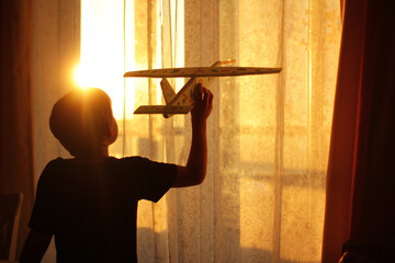 A little boy is playing with a toy airplane at home. childhood, travel dream, rich fantasy