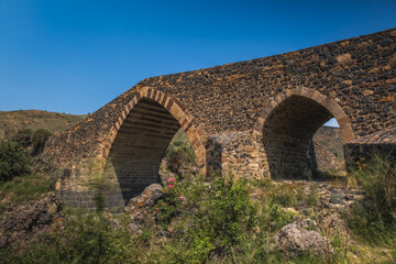 Ponte dei Saraceni. An ancient medieval bridge of Norman age located on the Simeto river. Adrano - Catania, in Sicily. Long exposure picture. June 2023