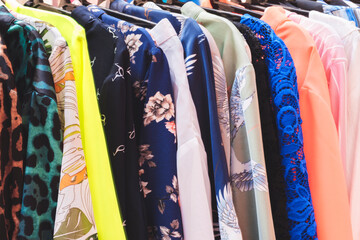 A rack of clothes with a yellow shirt on the left and a pink shirt on the right