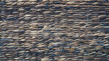 A close up of a wall made of brown and tan stones. The wall is made up of many small stones, and the stones are arranged in a way that creates a textured and rough appearance