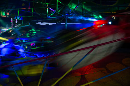 Juego mecanico girando rapidamente en la noche iluminado con luces de colores neon.