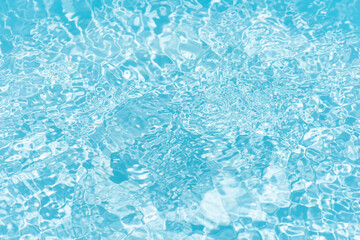 Blue water with ripples on the surface. Defocus blurred transparent blue colored clear calm water surface texture with splashes and bubbles. Water waves with shining pattern texture background.