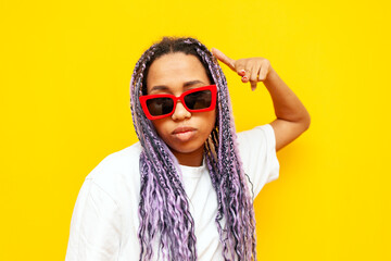 serious african american woman in glasses with colored dreadlocks threatens with her hand on a...