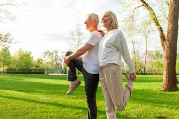elderly couple of seniors man and woman doing exercises and training in the park outdoors,...