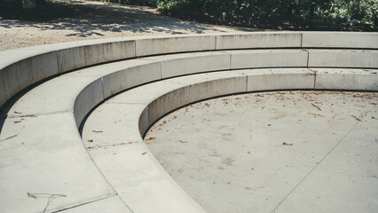 Close-up view of an empty outdoor amphitheater with curved concrete steps. The weathered surface...
