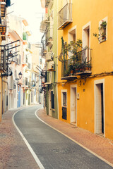 Naklejka premium View to beautiful narrow Villajoyosa street with multi-colored houses. La Vila Joiosa - coastal town, Valencian Community, Spain, by Mediterranean sea