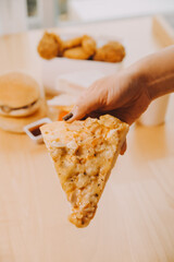 Cropped image of woman holding pizza slice at restaurant