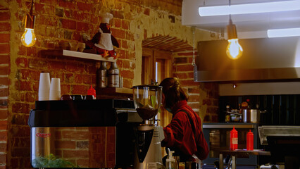 Beautiful hanging bulbs in the loft cafe. Stock footage. Barista making beverage at the coffee shop.