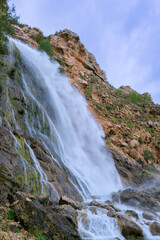 The image shows a powerful waterfall cascading down a rocky cliff.