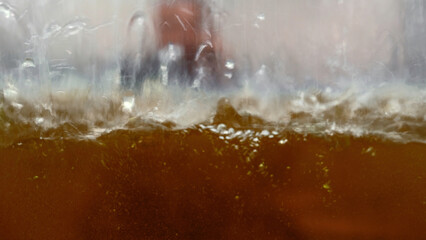 Mechanism spraying liquid substance inside glass container. Media. Industrial background at a plant.