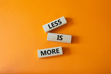 Less is More symbol. Concept words Less is More on wooden blocks. Beautiful orange background....