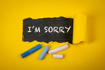 I’m sorry. Text under torn yellow paper on a blackboard