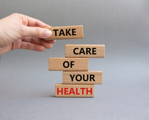 Health symbol. Wooden blocks with words Take Care of your Health. Doctor hand. Beautiful grey background. Health concept. Copy space.