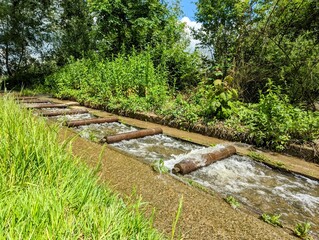 Steps of metal rollers on a downhill sluice control the flow of river water