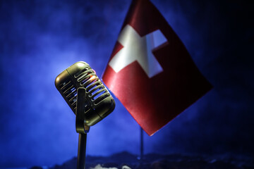 Microphone on a background of a blurry flag of Switzerland close-up. dark table decoration