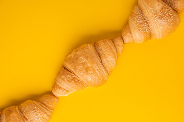 Flat lay of freshly baked croissants on the yellow background. Traditional French pastry with a...