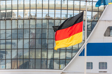 Flag of Germany in front of a large cruise ship.