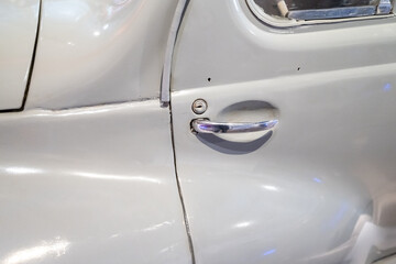 Door handle of a white vintage car.