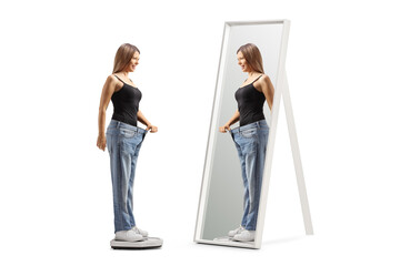 Happy young woman on a scale in front of a mirror