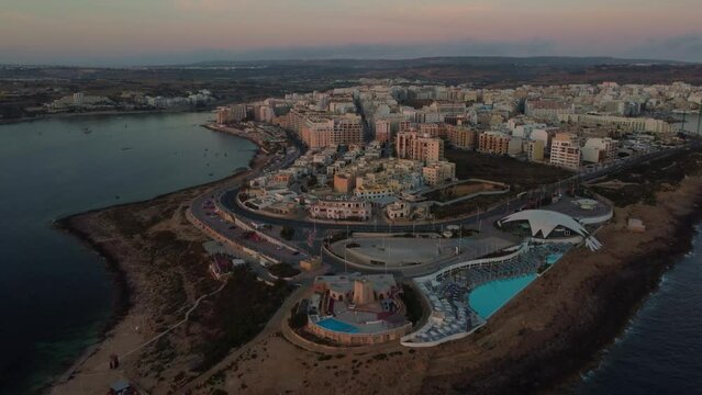 Qawra cityscape in the early morning, during the sunset. Revealing Qawra tower , and Malta National Aquarium. Aeral shot. High quality 4k footage