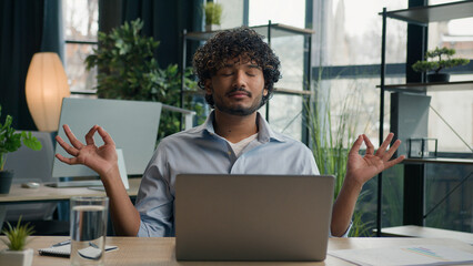Calm Arabian latin man Indian businessman meditate at office desk zen meditation relaxed male...