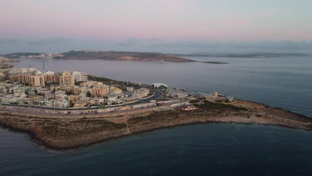 Qawra cityscape in the early morning, during the sunset. Revealing Qawra tower , and Malta National Aquarium. Aeral shot. High quality 4k footage