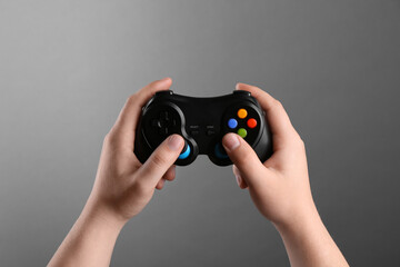 Woman using wireless game controller on grey background, closeup