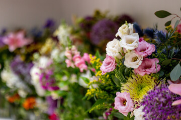 Vibrant bouquet of mixed flowers including roses, daisies, lilies, and more. The flowers are colorful, featuring purple, white, yellow, blue, and pink blooms, creating a beautiful, lush arrangement