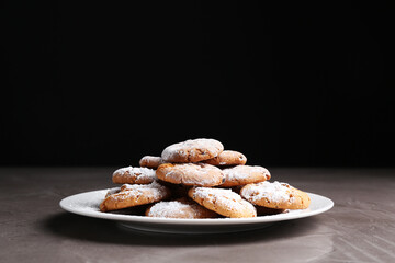Tasty cookies with sugar powder on grey textured table, closeup