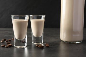 Coffee cream liqueur in glasses, bottle and beans on grey table