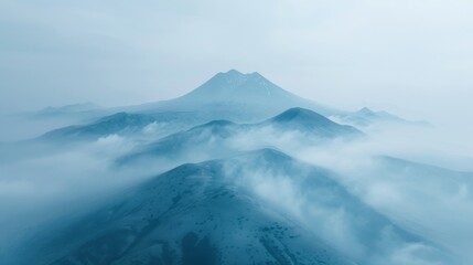Fototapeta premium Aerial view of the misty Demergy Mountain with surrounding hills under a hazy blue sky.