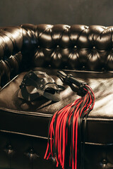 Whip and cat mask for BDSM on leather armchair