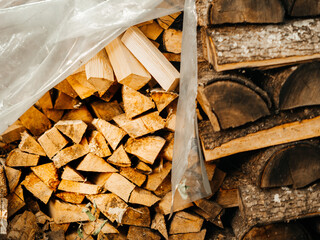 A pile of wood logs with some of them being cut. The pile is in the sun and has a rustic feel to it. Natural fuel for a home heating and cooking. Country side living.