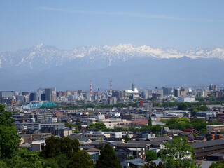Fototapeta premium 5月新緑の呉羽山富山県道44号富山高岡線を跨ぐ遊歩道吊橋から北アルプス剱岳立山連峰富山市街地を望む